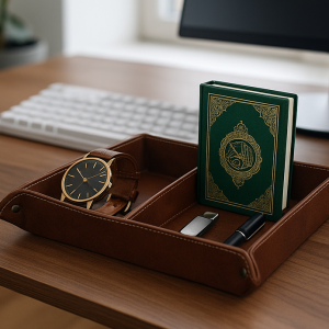 Leather desk organizer tray holding a wristwatch, a green Islamic book, pen, and USB drive on a wooden office desk.