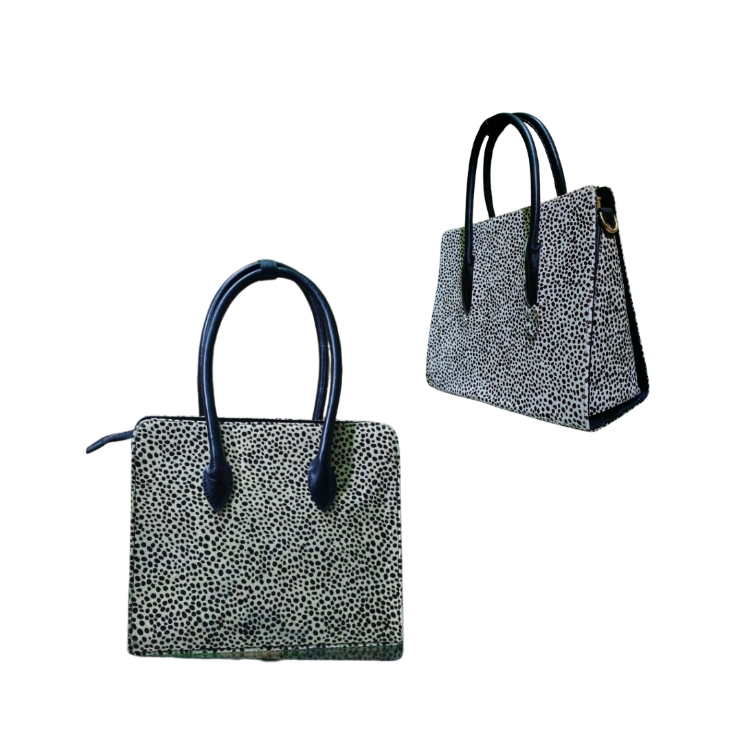 Black and white dotted textured women’s leather tote bag with black handles shown from front and side angles.