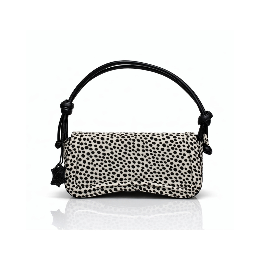 Black and white polka dot leather shoulder handbag with curved flap and black knotted straps